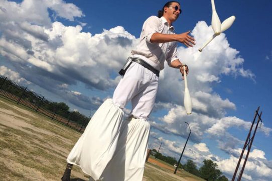 Stilt performer juggling outside